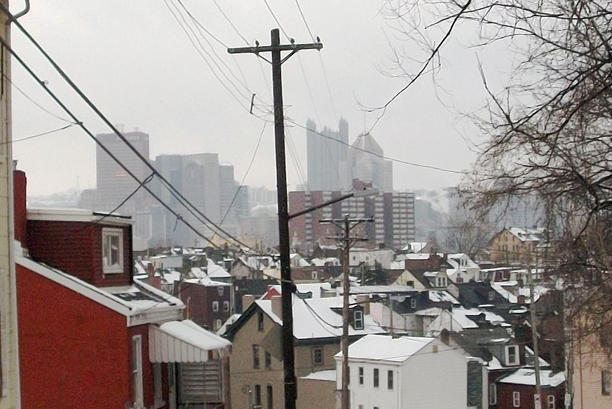 Snow covered houses in front of city buildings in Pittsburgh, PA.