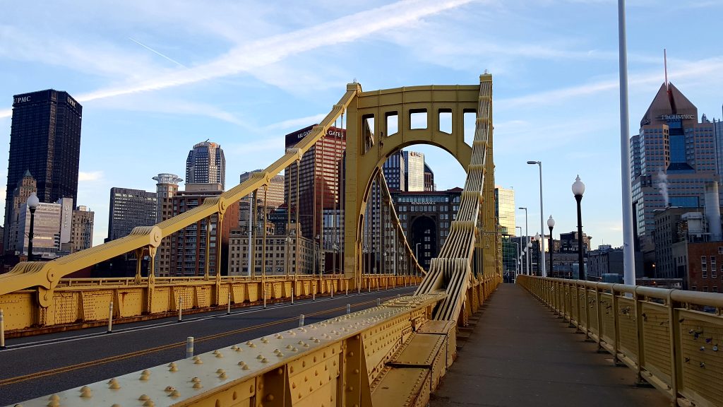 Yellow steel bridge in front of tall buildings.